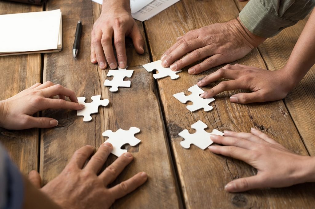 Find new solutions Closeup of businessman and woman with jigsaw puzzle pieces in office